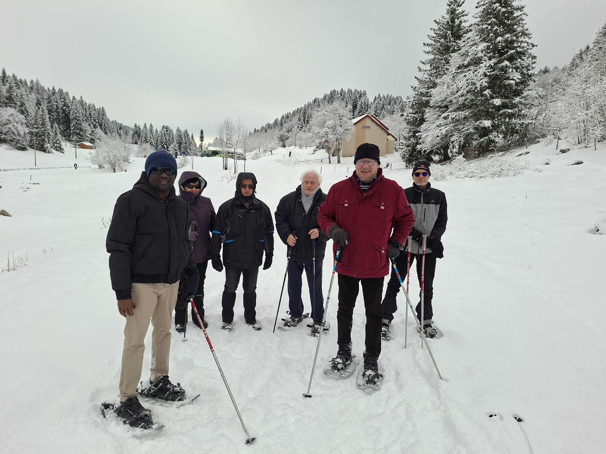 Le groupe dans la neige, des chalets et des sapins en fond, couverts de blancs.